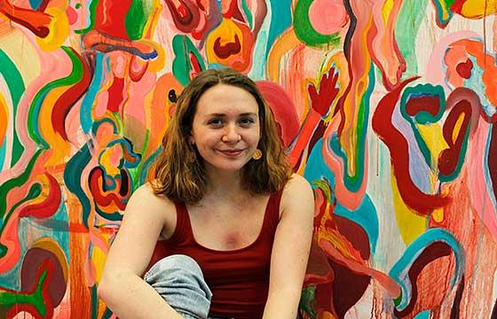 微笑的女人坐在一幅巨大的彩色画前